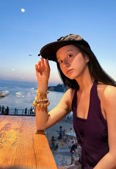 包上恩夕阳海边，坐在餐桌前，头戴鸭舌帽可爱生活照