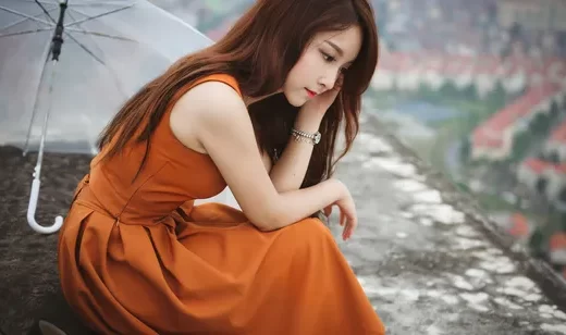 在阳台雨伞边，穿着橙色连衣裙的长发美女桌面壁纸
